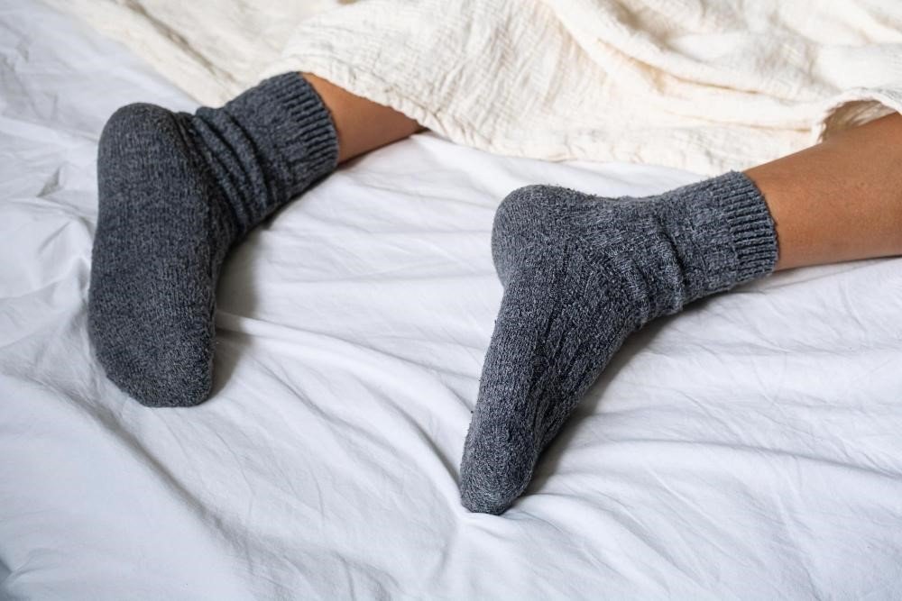 Pessoa dormindo com meia após passar hidratante para os pés
