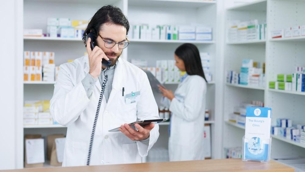 Farmacêutico de uma farmácia especializada, como a Natus Farma, atendendo um cliente pelo telefone. 