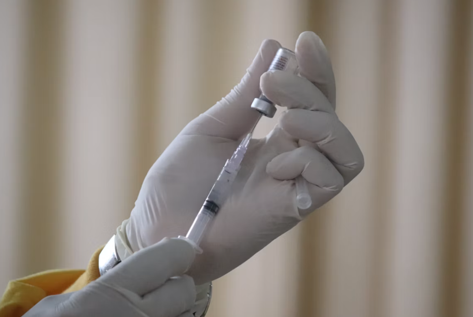 Mão de especialista preparando a dose de imunização.